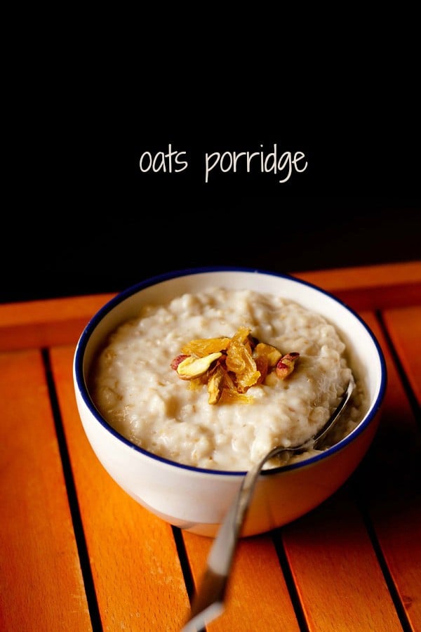 oats porridge topped with raisins and nuts in a blue rimmed white bowl with a spoon inside.