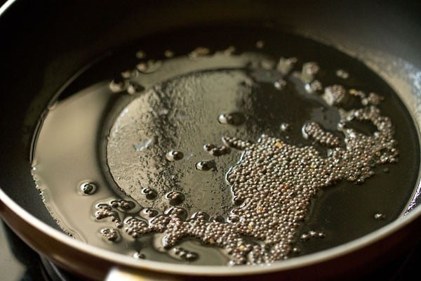 mustard seeds added to hot oil in a pan for poha upma. 