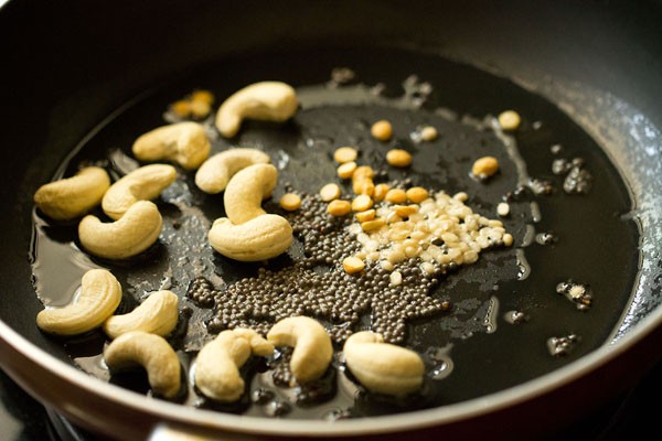 chana dal, urad dal and cashews added to hot oil for poha upma. 