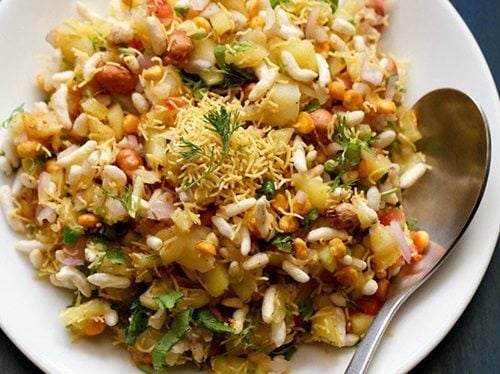 mango chaat served in a white bowl with a steel spoon.