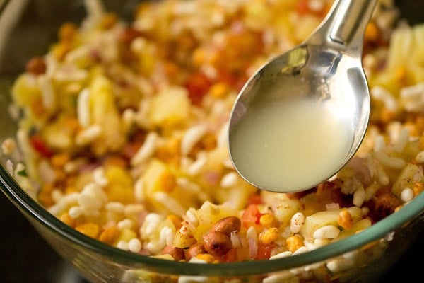 lemon juice added to raw mango-puffed rice mixture in the bowl. 