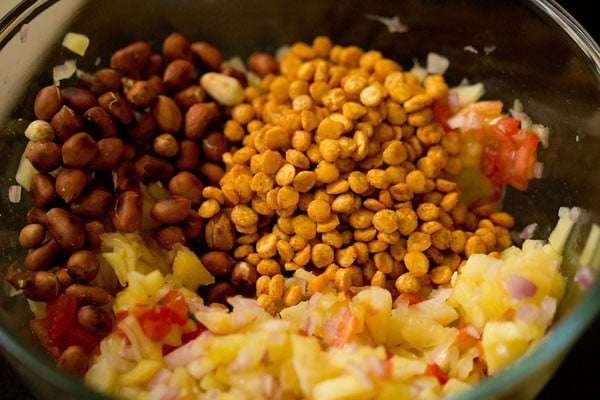 adding roasted peanuts and masala chana to the raw mango mixture in the bowl. 