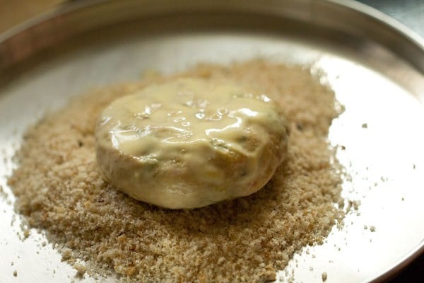 coating veg patty with bread crumbs in a plate