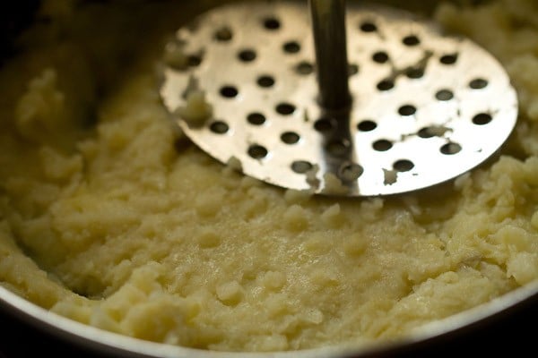 potatoes being mashed with a masher