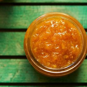 aam chunda in a glass jar on a green board.