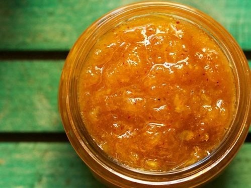 aam chunda in a glass jar on a green board.