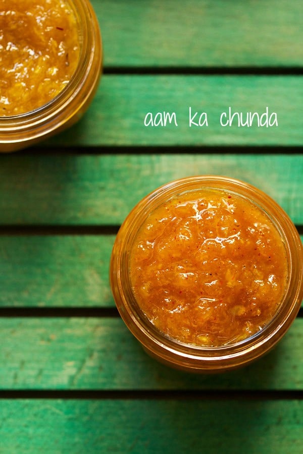 aam chunda kept in a glass jar on a green board with text layovers.