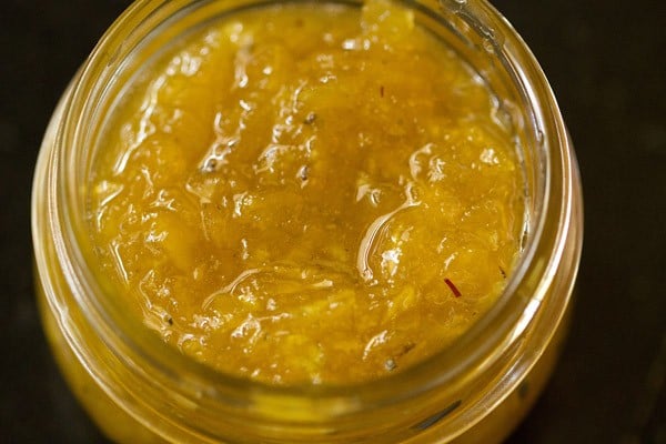 cooked aam ka murabba spooned in a glass jar. 