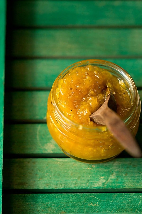 aam ka murabba in a glass jar with a wooden spoon. 