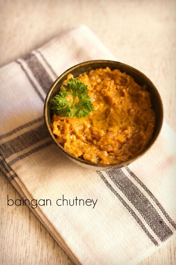 brinjal chutney garnished with coriander leaves and served in a ceramic bowl with text layover.