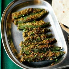 bharli bhendi served in a steel plate with chapattis and text layovers.