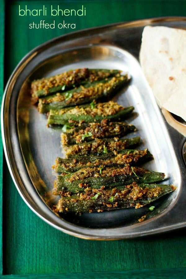 bharli bhendi served in a steel plate with chapattis and text layovers.