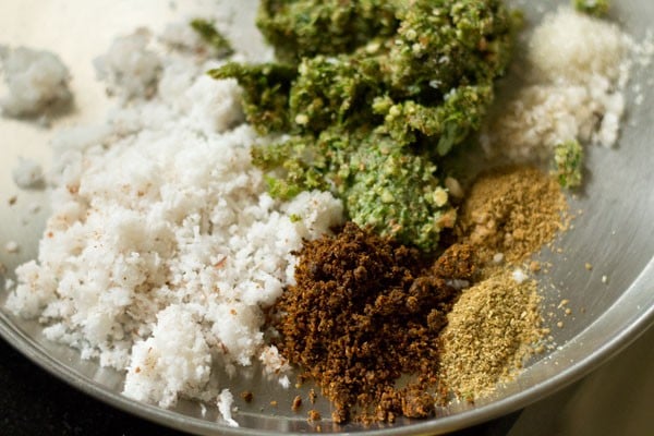 ground mixture, grated fresh coconut, cumin powder, coriander powder, goda masala, lemon juice, sugar and salt added on a plate. 