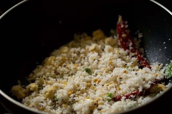 coconut mixed with rest of the spices and herbs in black pan. 