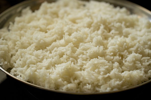 cooked rice spread on a large steel plate. 