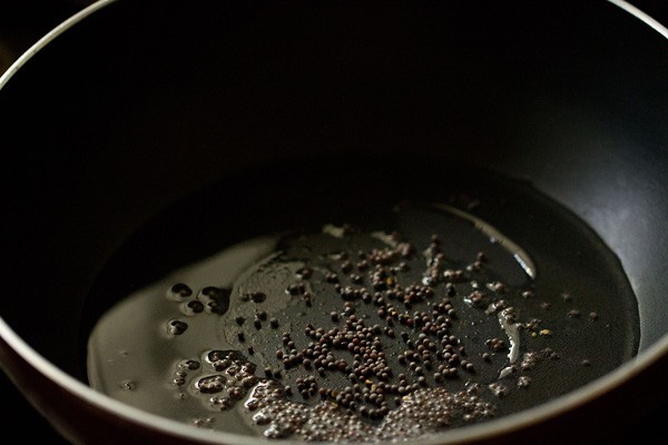 mustard seeds in hot coconut oil in a black pan. 
