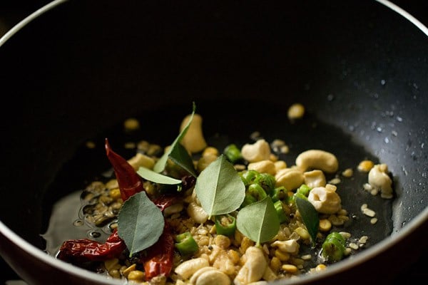 dried red chilies, curry leaves, chopped green chilies and asafoetida added to pan. 