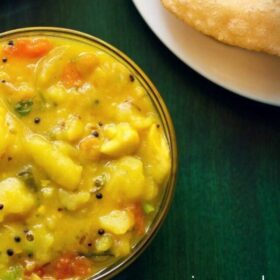 poori masala and aamras, served in two glass bowls with poori on a white plate with text layover.