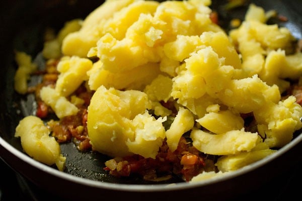 crumbled potatoes added to the onion-tomato mixture to make dahi aloo.