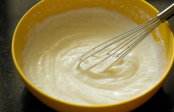 whisking fresh curd in a yellow bowl. 