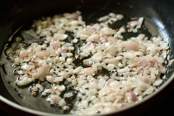 sautéing onions in the pan to make dahi aloo.