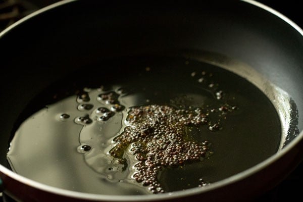 mustard seeds in oil in pan.