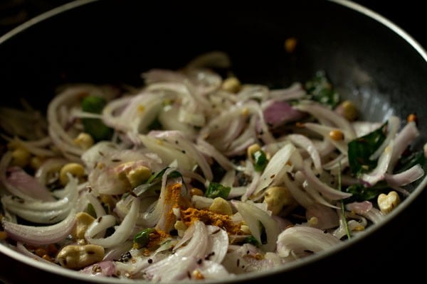 turmeric powder on sliced onions in pan.