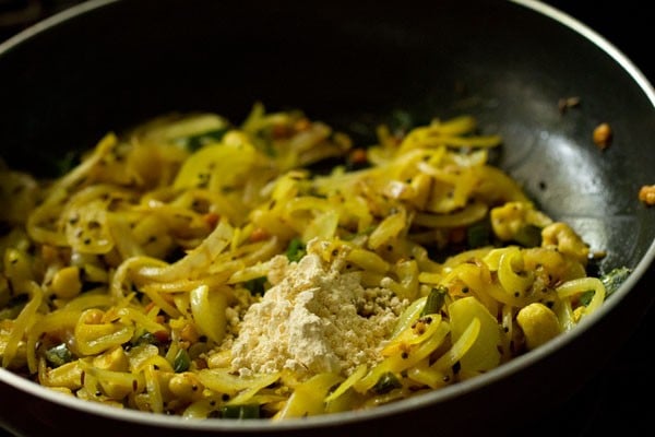 gram flour on top of cooked onions in pan.