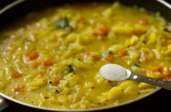 salt being added to poori masala in pan.