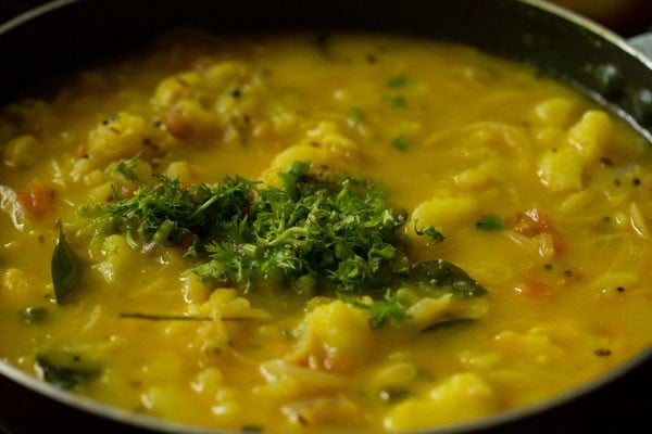 chopped cilantro on top of puri curry in pan.