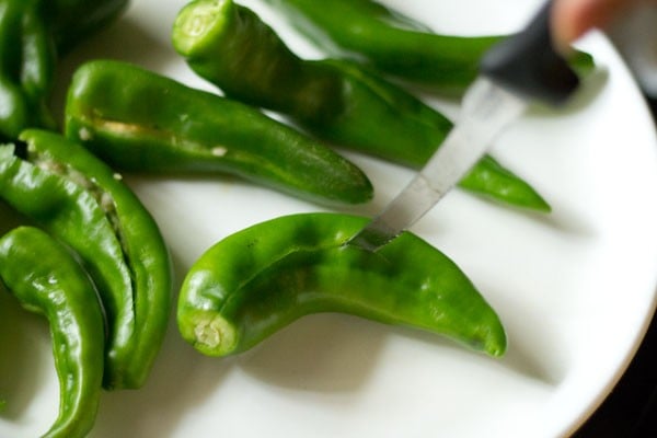 slitting chilies with a knife for mirchi bada. 