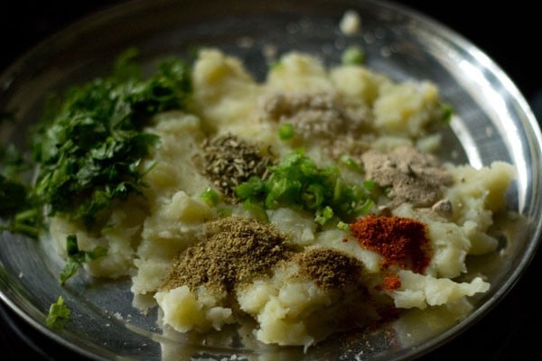 chopped green chili, chopped coriander leaves, crushed fennel seeds and spice powders added to the mashed potatoes for rajasthani mirchi vada. 