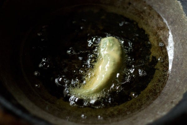batter coated stuffed green chili added gently in the hot oil for frying. 