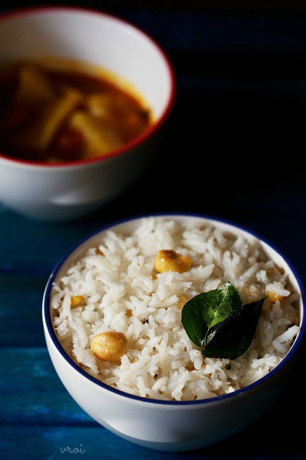 coconut rice with two curry leaves on top of it in a blue rimmed white bowl. 