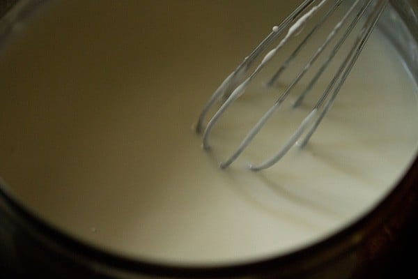 whisking curd with a wired whisk in a bowl