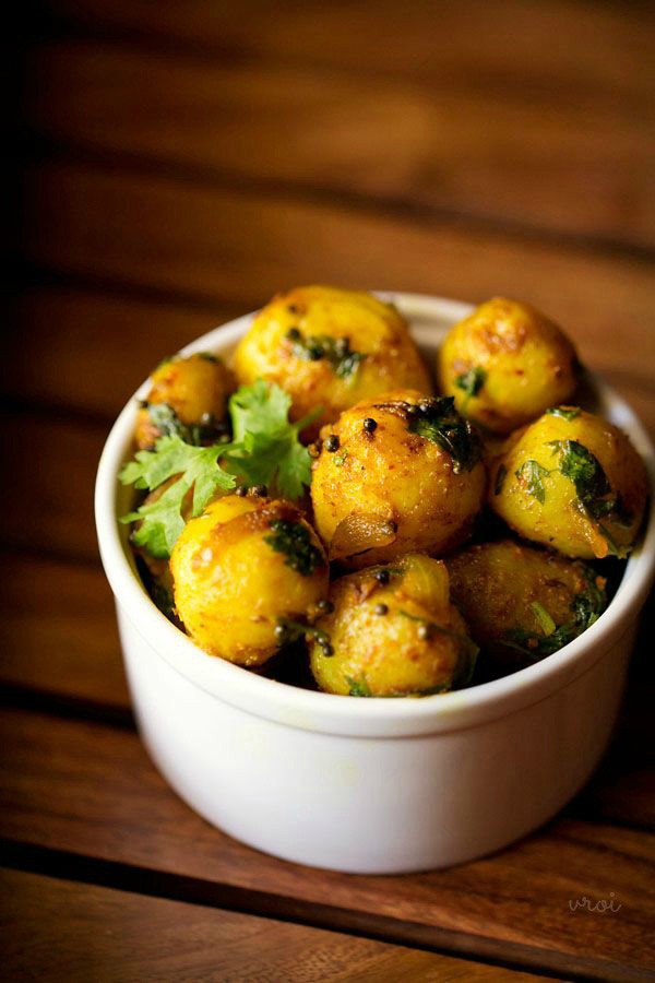 baby potato fry garnished with a coriander sprig and served in a white bowl. 