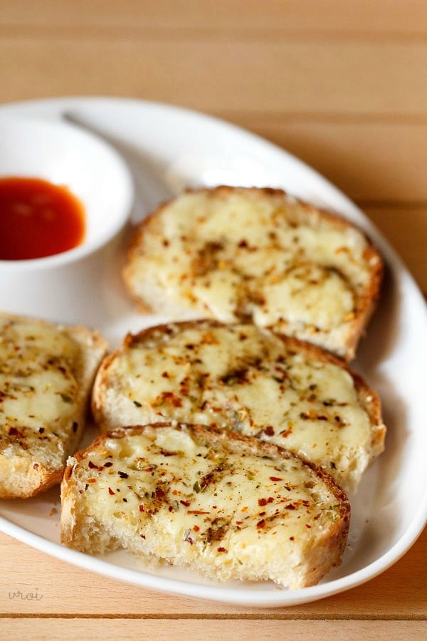 cheese garlic bread served on a plate with tomato ketchup on the side. 