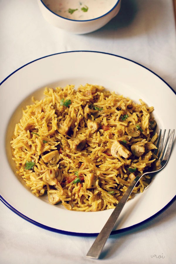 Round white plate with fork and finished mushroom biryani dish.