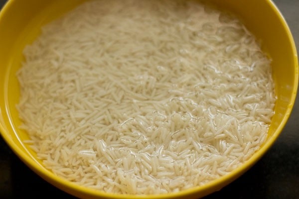 Rice engulfed in water in yellow bowl.