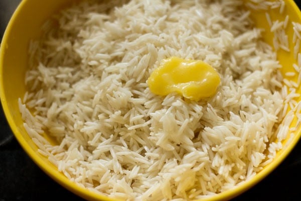 Rice with scoop of ghee on top in yellow bowl.