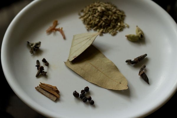 Tej patta and whole spices on a round white plate.