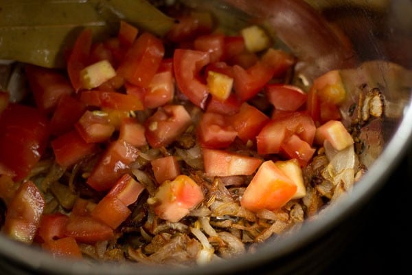 Browned onions and chopped tomatoes in pan