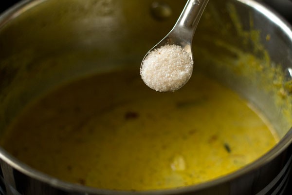 Teaspoon of salt being added to gravy mixture in pan