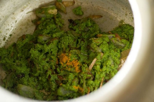 adding turmeric to ground coriander-spices paste and onions