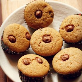 healthy chocolate chip muffins arranged neatly on a round plate placed on a bamboo board