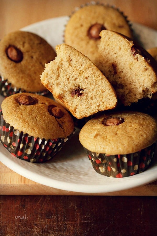 eggless chocolate chip muffin cut in half, laying on top of other chocolate chip muffins.