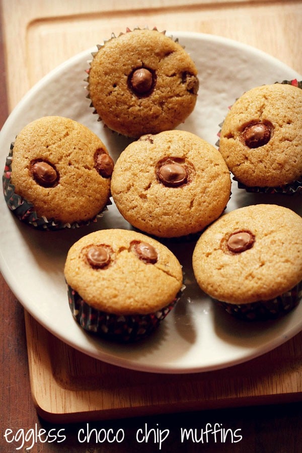 eggless chocolate chip muffins arranged neatly on a round plate placed on a bamboo board