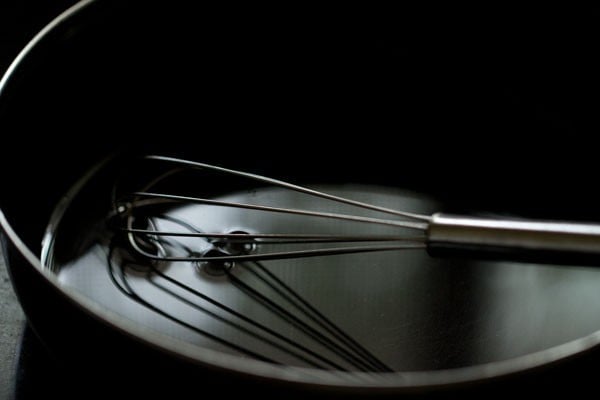 Water in black bowl with whisk sitting inside.