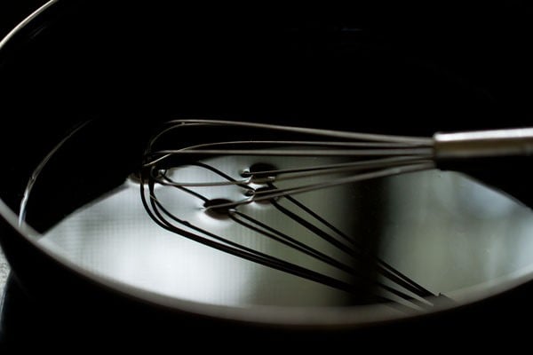 Water in black bowl with whisk sitting inside.