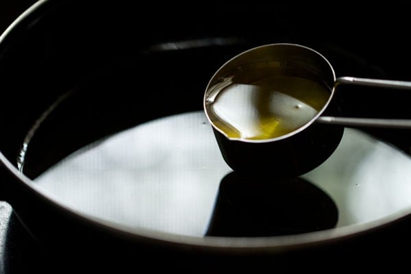 Oil in measuring cup being poured into black bowl.